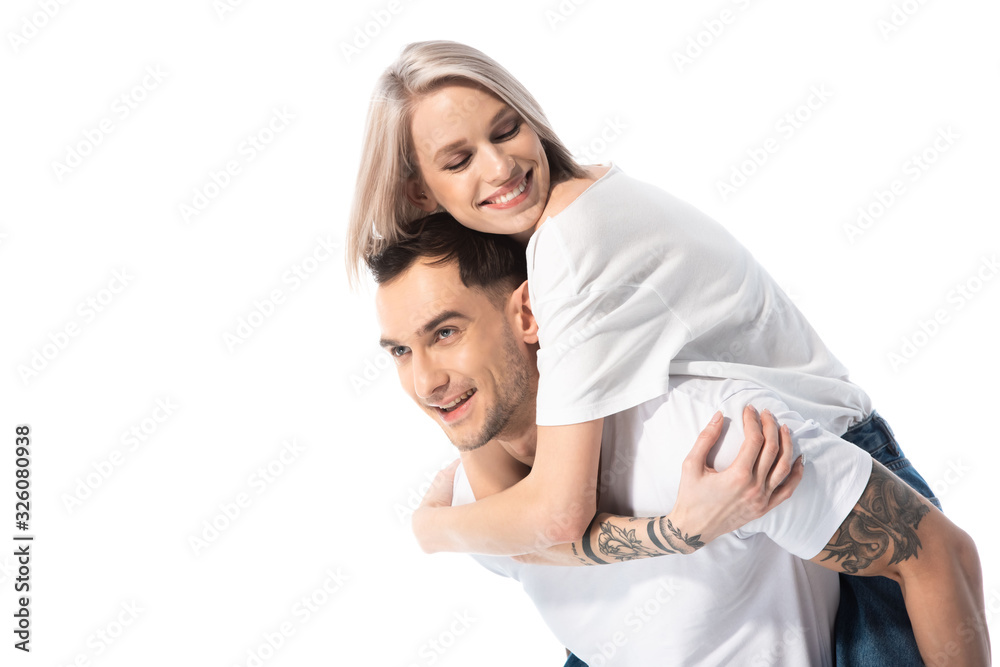 happy young tattooed couple piggybacking isolated on white