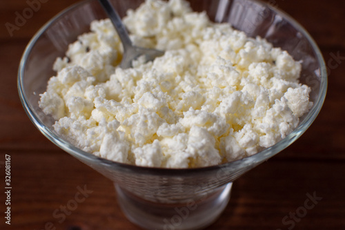 Homemade rustic crumbly cottage cheese with milk on a wooden background. Still-life.