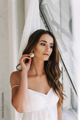 Portrait of a young beautiful woman. Bride in elegant classic wedding dress. Morning of the bride. Wedding preparations.