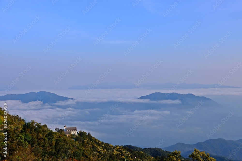 The gorgeous view of the fog moves along the mountains in the mountain range with big house on the mountain as foreground at Ba Na Hills, Da Nang, VIETNAM.