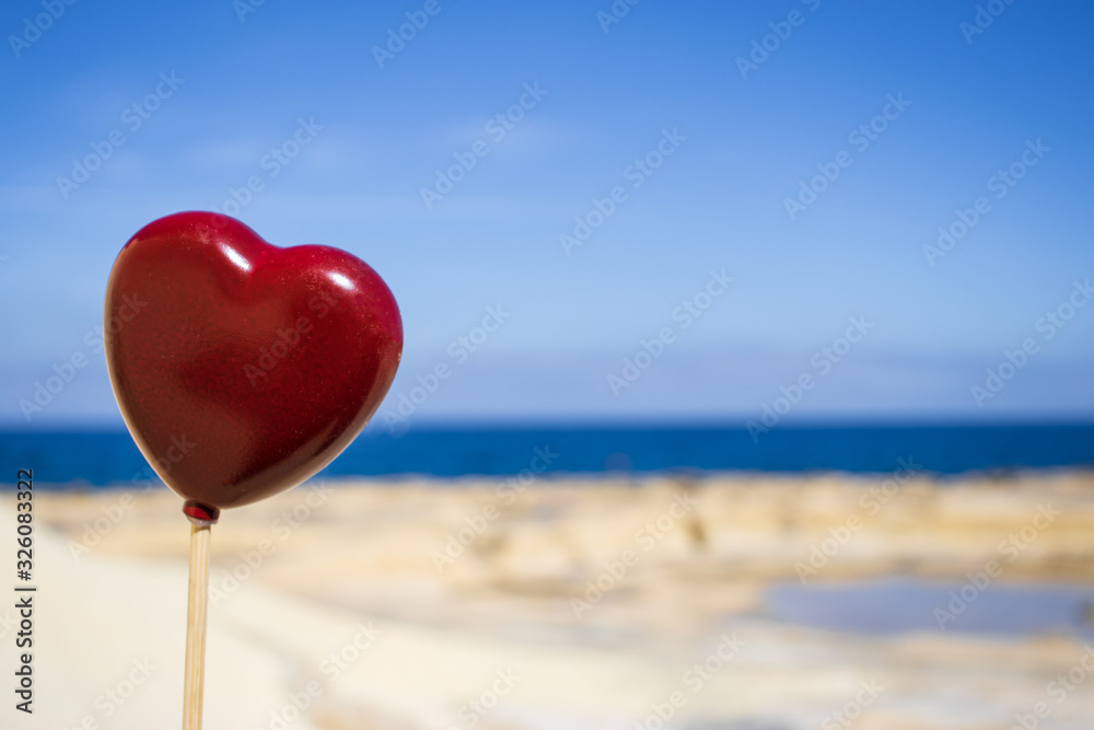 Red heart shape on beach by the ocean. Love holiday background Red heart shape on beach by the ocean. Love holiday background