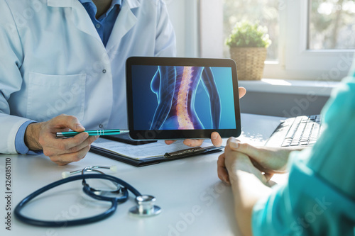 Konstfotografi doctor and patient talking about back pain treatment in clinic office