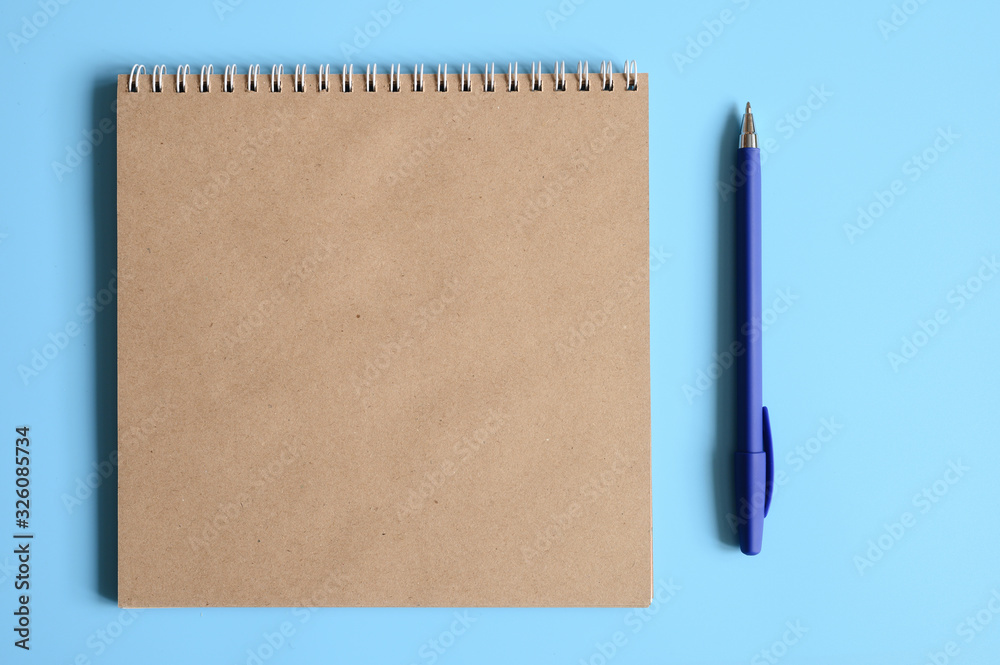 notebook or sketchbook made of craft paper and a pen on a blue background. space for text notebook or sketchbook made of craft paper and a pen on a blue background. space for text