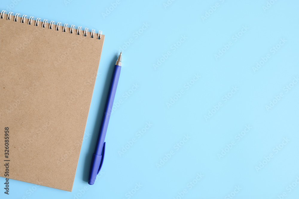 notebook or sketchbook made of craft paper and a pen on a blue background. space for text notebook or sketchbook made of craft paper and a pen on a blue background. space for text