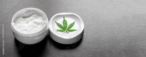 Cannabis CBD balm natural product, cosmetic cream from natural hemp, moisturizing lotion with CBD content. Hemp topical cream ointment with cannabis leaf with copy space