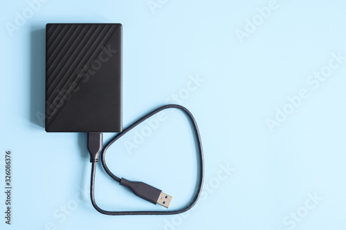 external hard drive black color with connection cable on blue background