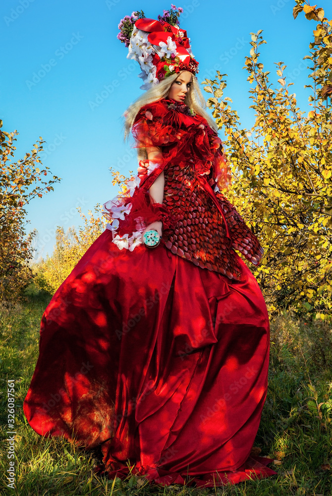 Sensual blond girl in fantasy red fairy tale stylization in apple park. Sensual blond girl in fantasy red fairy tale stylization in apple park.