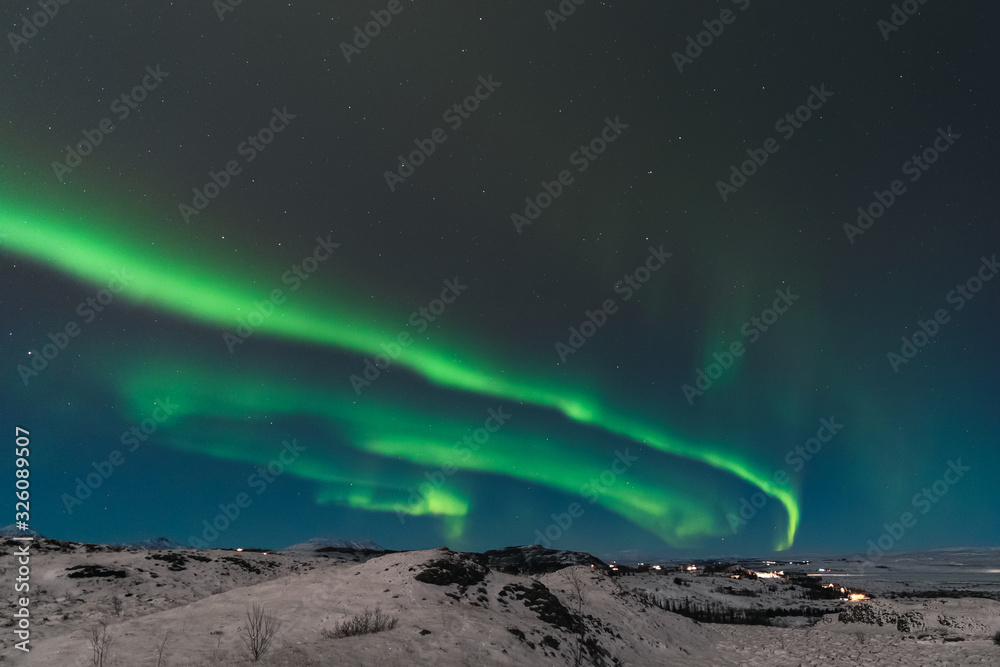 A beautiful northern lights also called Aurora Borealis over the Iceland. Winter time in Scandinavia is very magical and brings a lot of tourists from all over the world to see it