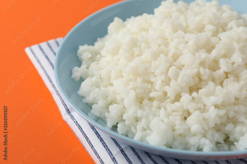 Bowl with boiled rice on orange background, close up Bowl with boiled rice on orange background, close up