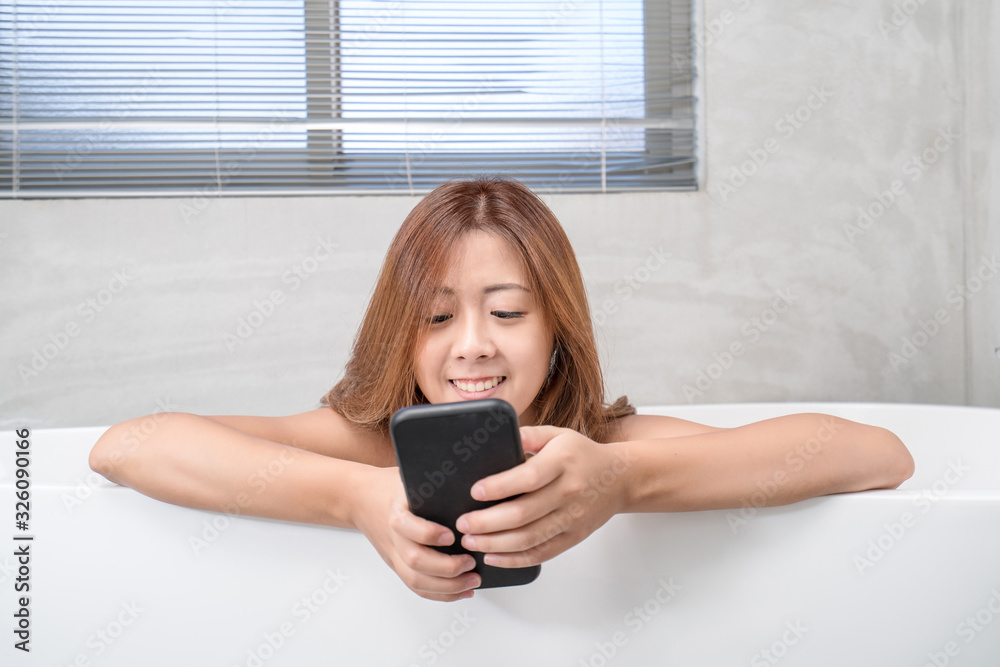 Young and beautiful girl using phone relaxing in the retro bath indoors Young and beautiful girl using phone relaxing in the retro bath indoors