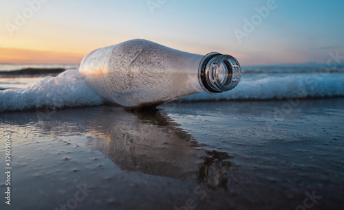 Plastic bottle litter and trash washed up on a sunny sandy luxurious beach destination. Environmental plastic pollution issue causing world  news. Health disaster on shores across the world.