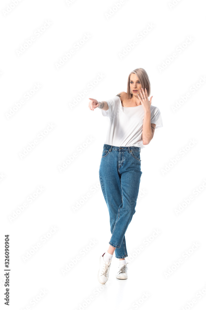 shocked young tattooed girl pointing with finger away isolated on white shocked young tattooed girl pointing with finger away isolated on white