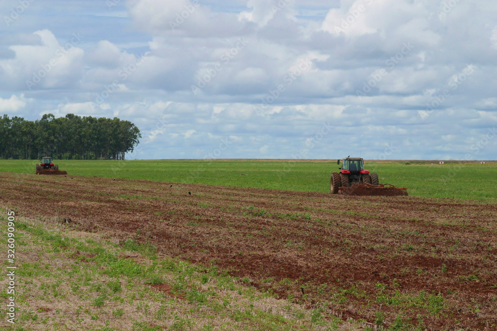 Trator no campo plantando soja, 2 tratores, solo preparado, céu com nuvens anunciando chuva Trator no campo plantando soja, 2 tratores, solo preparado, céu com nuvens anunciando chuva