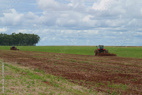 Trator no campo plantando soja, 2 tratores, solo preparado, céu com nuvens anunciando chuva