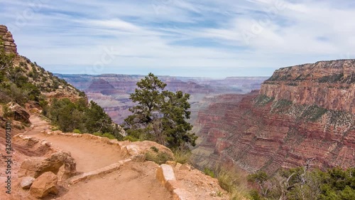 A Stone Path On The Rim Of The Boulder With Planted Trees And Plants On The Side Slope Under The Cloudy Sky. -wide shot photo