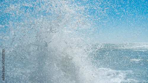 Water splash of powerful waves on blue sky background. Sea foam crashing close up , huge waves. Water texture.