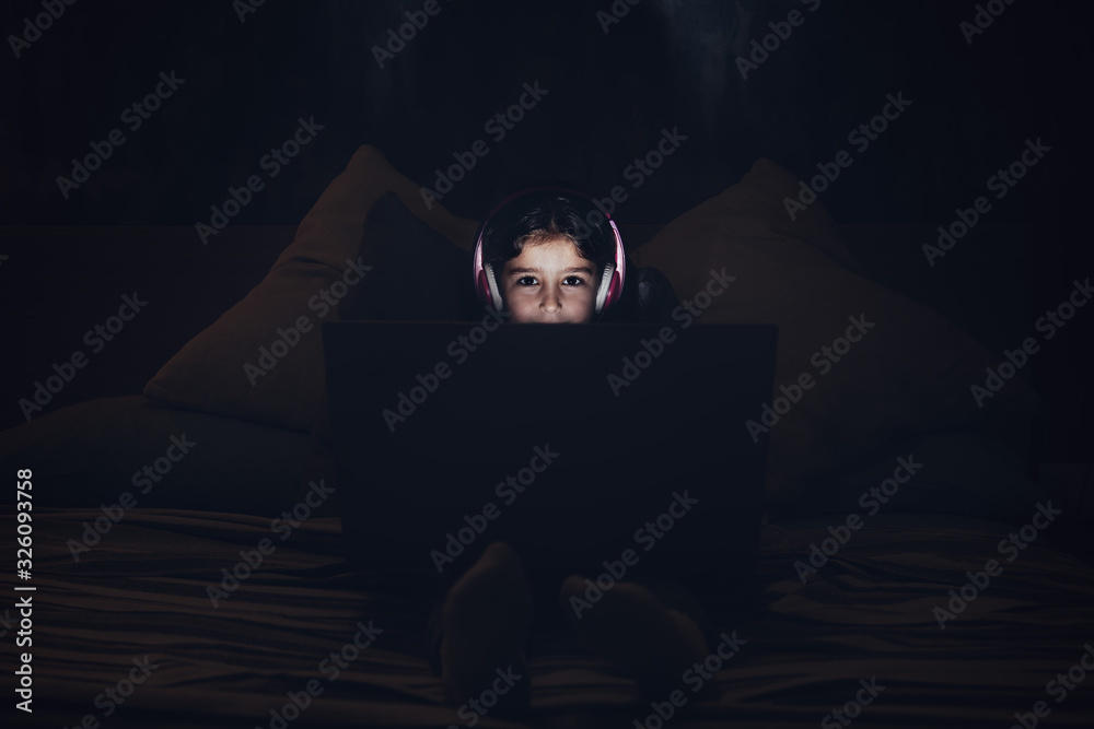 little girl with a computer in the darkness at bed little girl with a computer in the darkness at bed