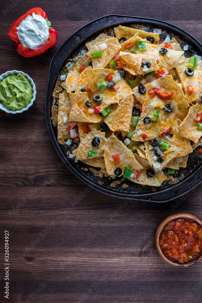 A top down view of a baking sheet filled with loaded Nachos ready for eating. A top down view of a baking sheet filled with loaded Nachos ready for eating.