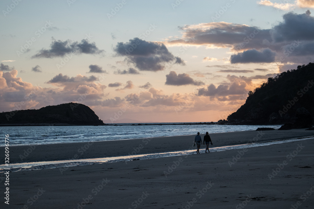 Couple walking on a remote beach at sunrise