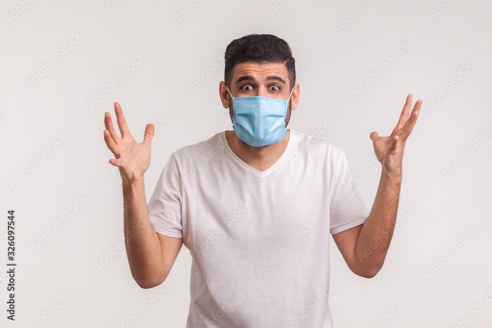 Panicking man in hygienic mask raising hands in fear, gesturing question what to do, afraid of sudden coronavirus outbreak, lack of knowledge about novel influenza 2019-nCoV. studio shot, isolated Panicking man in hygienic mask raising hands in fear, gesturing question what to do, afraid of sudden coronavirus outbreak, lack of knowledge about novel influenza 2019-nCoV. studio shot, isolated