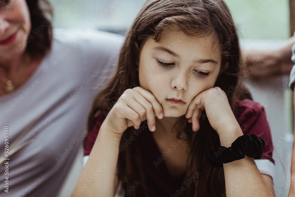 Thoughtful girl sitting with grandmother in restaurant