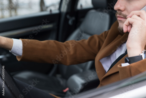 portrait of a young guy thirty years old. Businessman in a business style of clothing. Rides in the passenger seat at the office to work, solving problems on the smartphone, talking on the phone