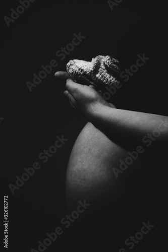 Embarazada cargando zapatitos de bebe en la mano blanco y negro photo