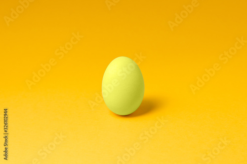 one pastel yellow color egg in center on yellow background easter concept design