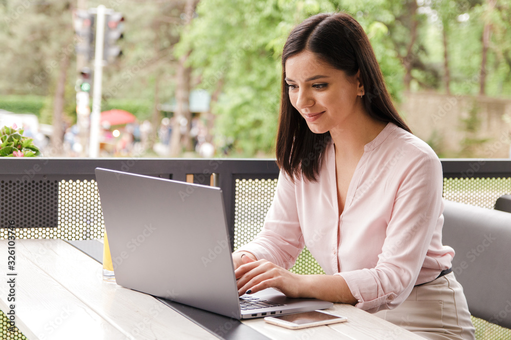 cheerful young businesswoman smiling working with energy on computer on terrace in cafe cheerful young businesswoman smiling working with energy on computer on terrace in cafe