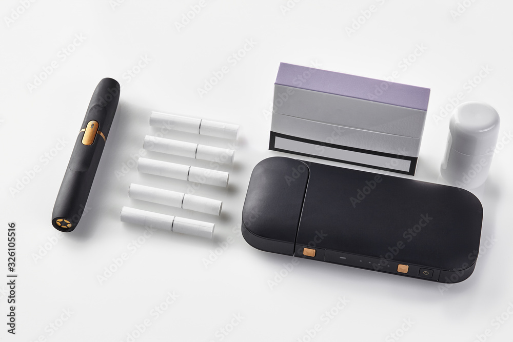 New generation black electronic cigarette battery, cleaner, pack with purple side, five heatsticks isolated on white. Heating tobacco system. Close up New generation black electronic cigarette battery, cleaner, pack with purple side, five heatsticks isolated on white. Heating tobacco system. Close up