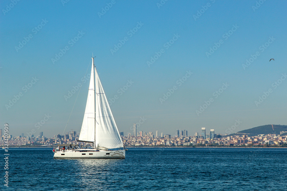 One White Yacht on the blue sea. Beautiful big city Istambul, Turkey with modern buildings