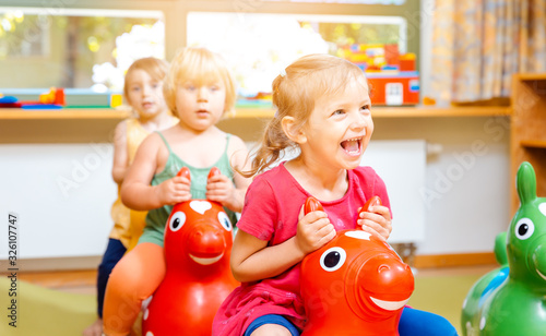 Canvastavla Little girls riding on play horses in kindergarten