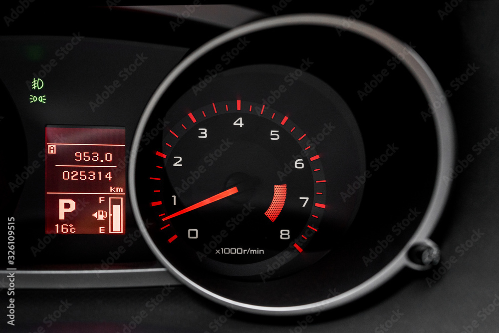 Car dashboard with speedometer and illuminated fuel consumption indicator close up. Modern electronics inside vehicle