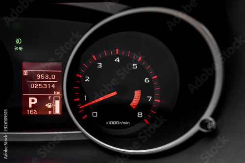 Car dashboard with speedometer and illuminated fuel consumption indicator close up. Modern electronics inside vehicle