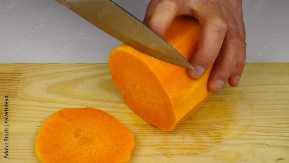 A man slices into thin pieces a pumpkin on a cutting board A man slices into thin pieces a pumpkin on a cutting board