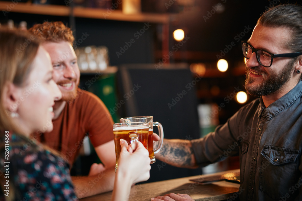 Caucasian couple standing in pub, toasting with beer and having fun. Nightlife.