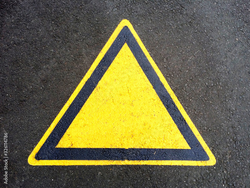 Blank triangle hazard, attention, warning, danger sign on the black asphalt. Empty triangular sticker in yellow and black colors. Use it in all your designs © kelifamily