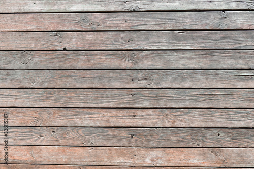 Close-up of wooden texture of wall boards driven in with rusty nails, weathered planks with deep cracks and worn brown paint. Abstract rustic background for design, blank template