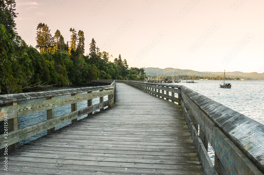 Deserted boardwalk along the the shore of a bay at sunset. Sooke, BC, Canada