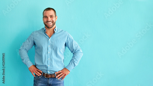 Happy man in front of blue wall with copy space