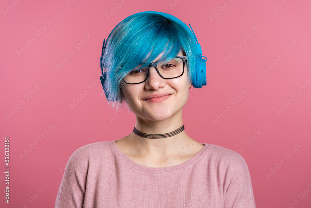 Pretty young girl with turquoise hair having fun, smiling, dancing with blue headphones in studio on colorful background. Music, dance, radio concept. Pretty young girl with turquoise hair having fun, smiling, dancing with blue headphones in studio on colorful background. Music, dance, radio concept.
