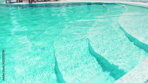 edge of the swimming pool with clear blue water at sunny summer day photo