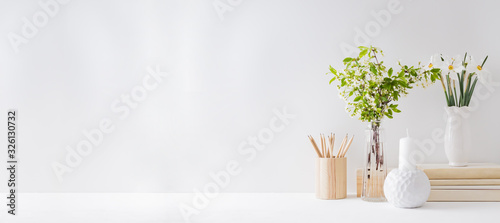 Home office, interior for bloggers workplace with white daffodils in a vase, office supplies on a light background photo