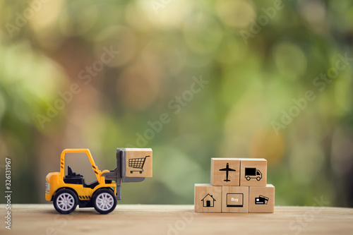 Logistic network distribution and cargo freight concept: Mini fork-lift truck moves a pallet with wooden block with icon. depicts delivering goods or products around globe in e-Commerce.