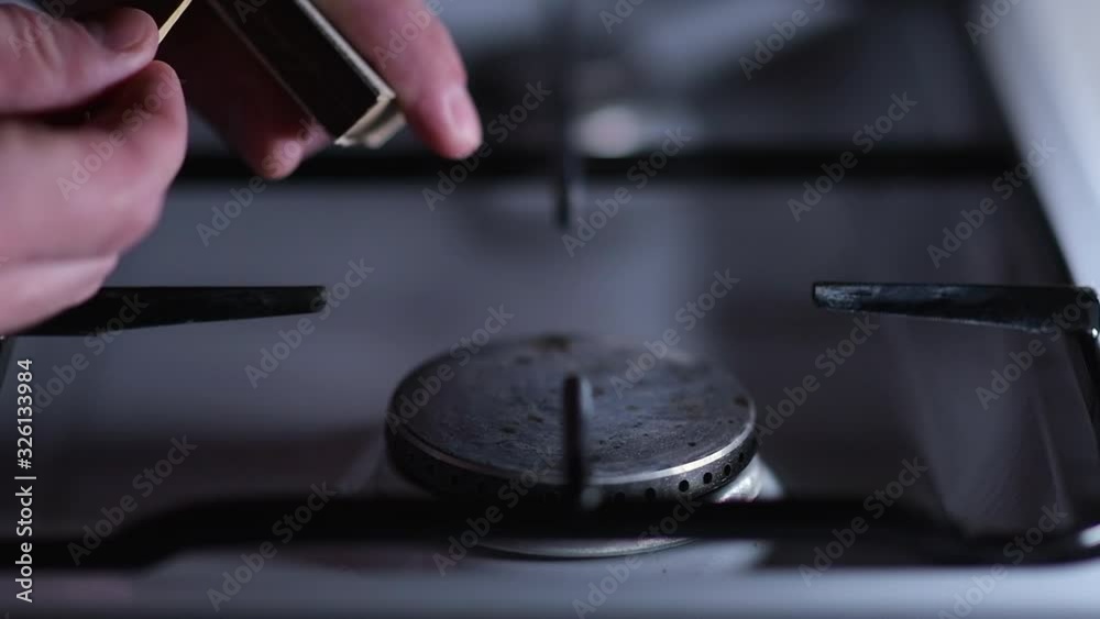 Ignition of a gas stove, close-up, slow motion. Igniting a match and igniting gas on a gas stove with it Ignition of a gas stove, close-up, slow motion. Igniting a match and igniting gas on a gas stove with it