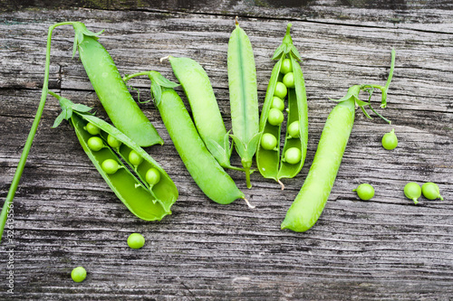 Fresh green pea pods on a rough wooden old surface, top view, copy space
