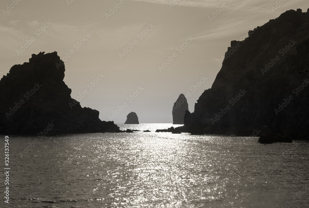 silhouette of rock stacks outcropping from the sea near the island of Filicudi at sunset, Aeolian Islands, Messina, Sicily, Italy