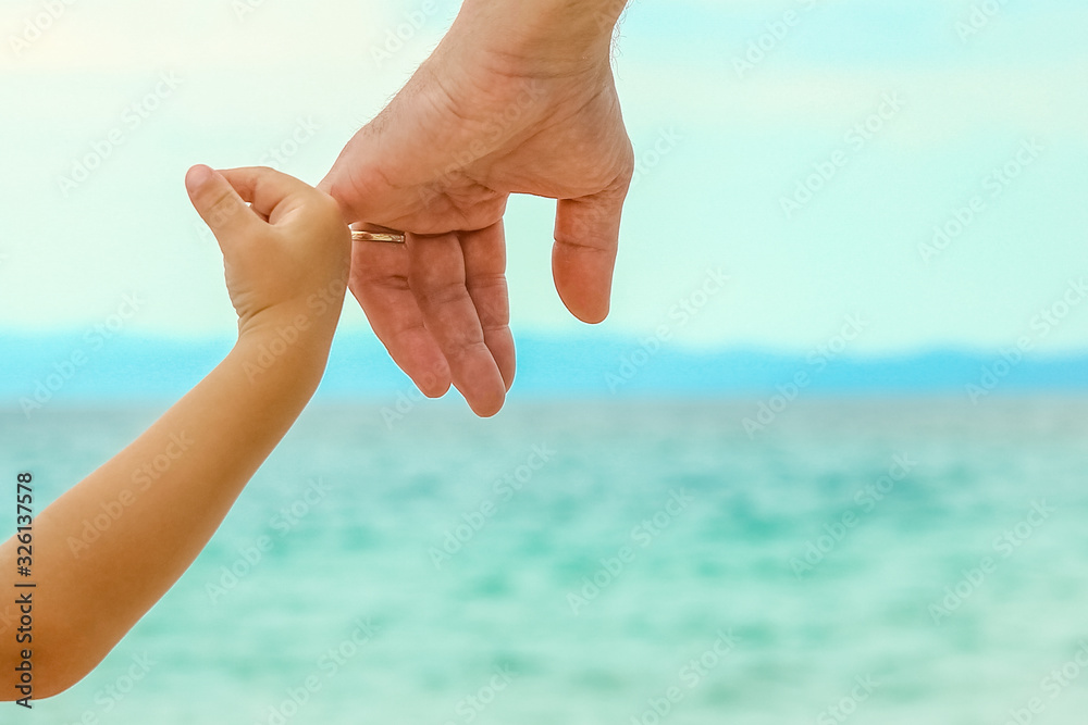 beautiful hands of a happy parent and child by the sea in nature
