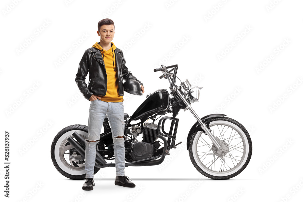 Obraz premium Young guy holding helmet and posing next to a custom motorbike
