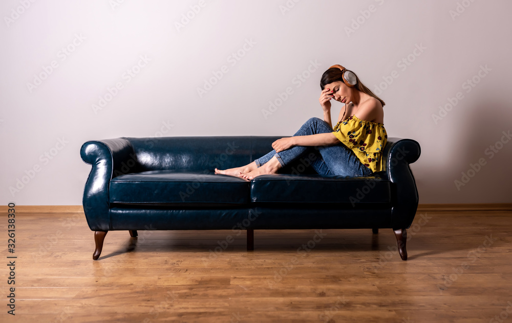 Obraz premium A serious woman listening to music on a sofa